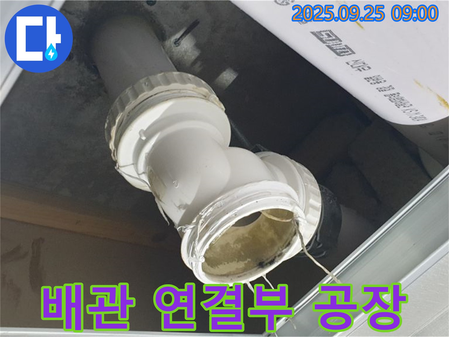 공장 천장 배관 연결 부위에서 누수가 발생하여 물이 떨어지고 있는 모습입니다 - 생산 중단으로 이어질 수 있습니다.