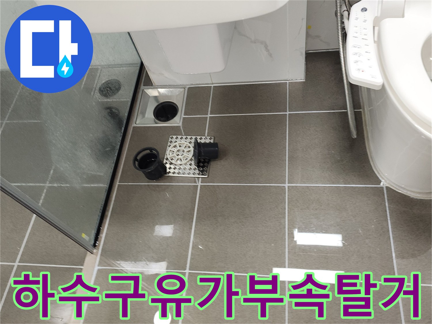 화장실 배수구 주변의 탈거된 유가 부품과 배관 입구 근접 사진