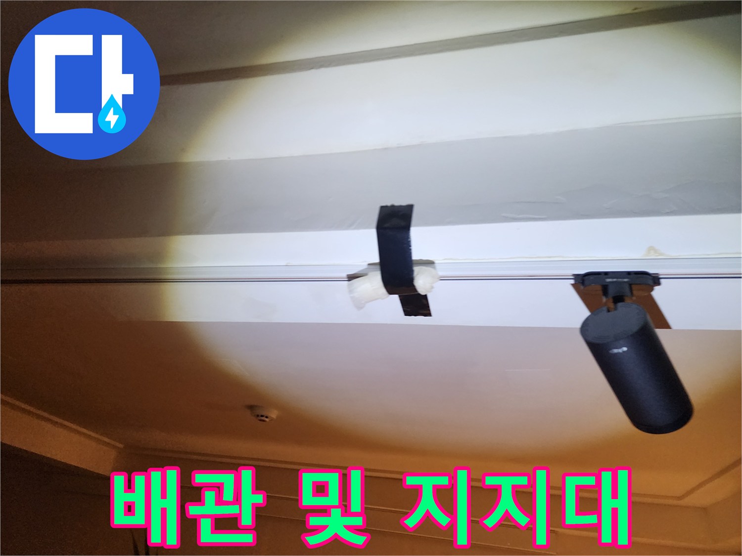 천장에 고정된 검은색 배관 고정 장치입니다.