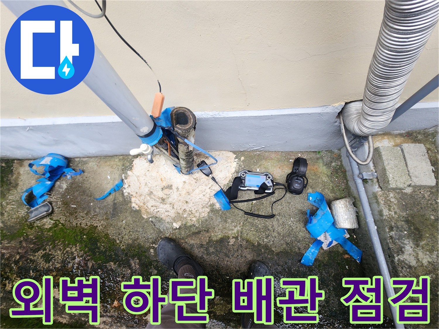 건물 외벽 아래쪽 배관 파손 부위와 탐지 장비의 모습