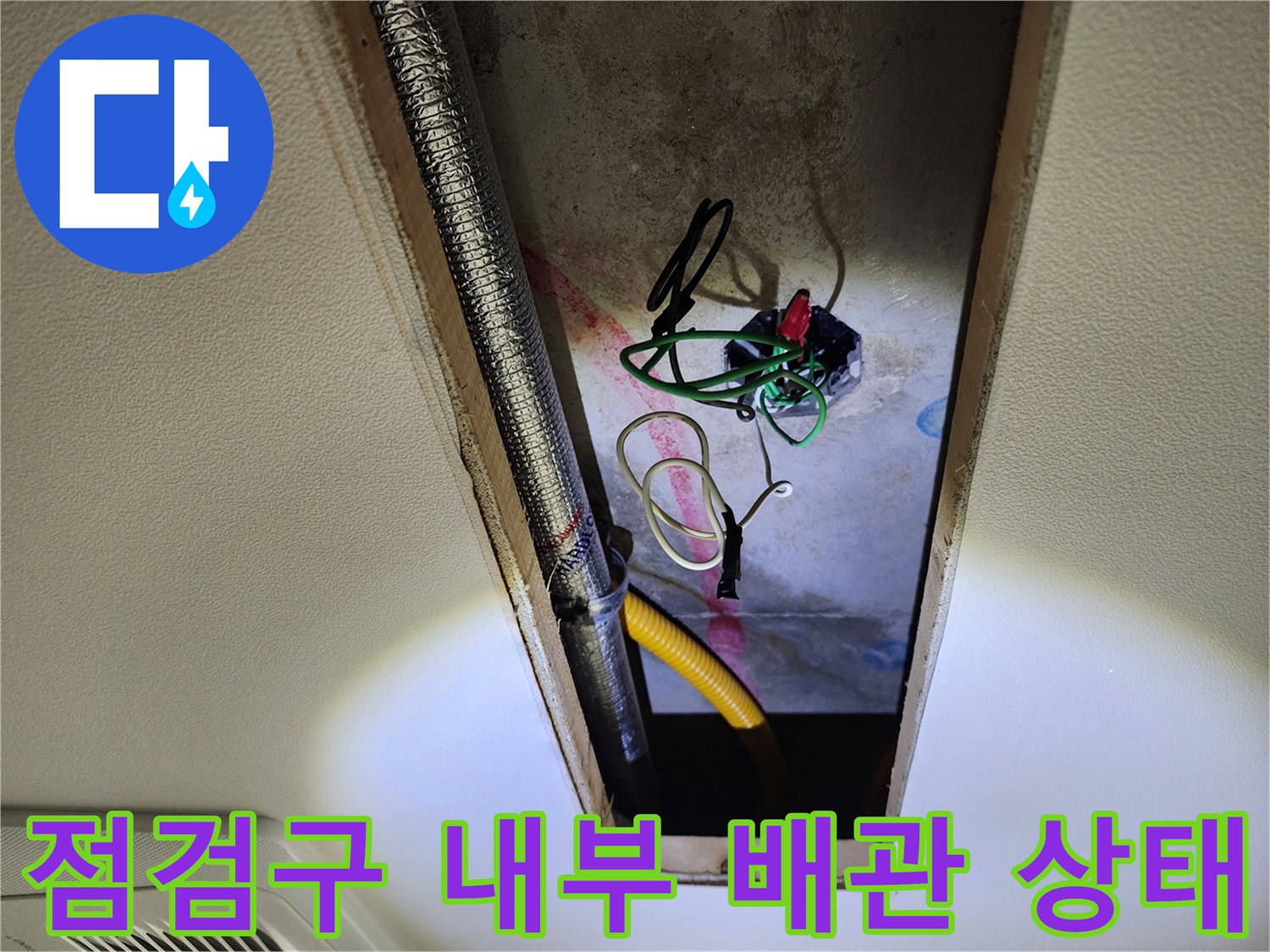 천장 점검구 안쪽의 노출된 배관과 전기 전선 모습