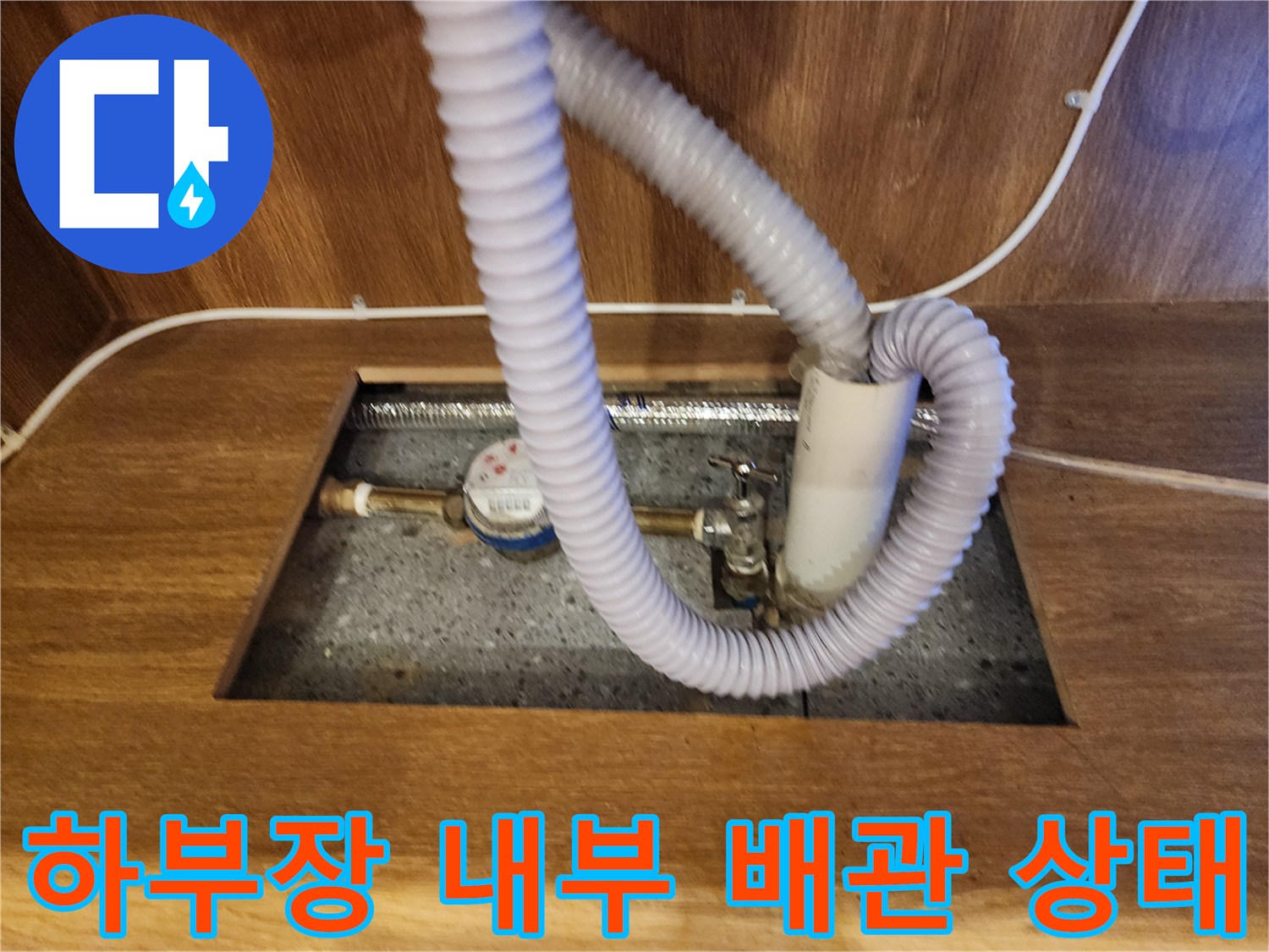싱크대 하부장 바닥에 노출된 온수기 배관과 호스 구조
