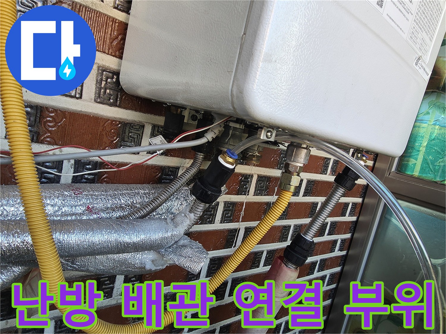 금속 유니온과 노란색 호스가 연결된 보일러 하부 모습