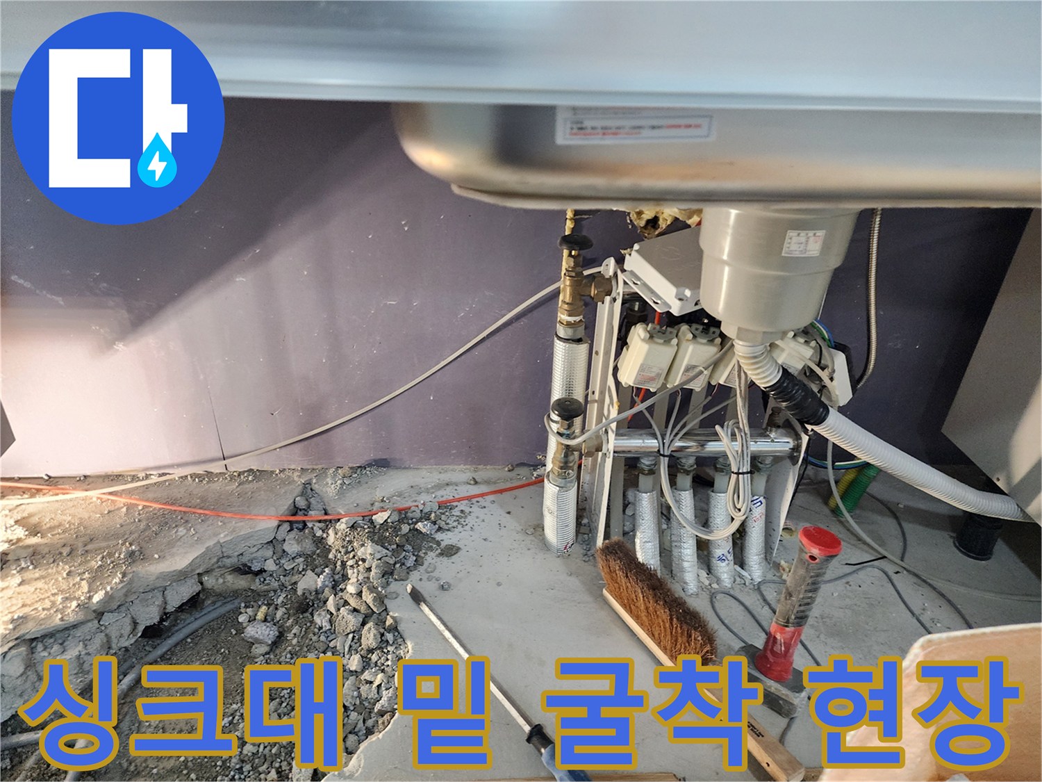 싱크대 하단 부위-노출된 매립 배관과 젖은 지면