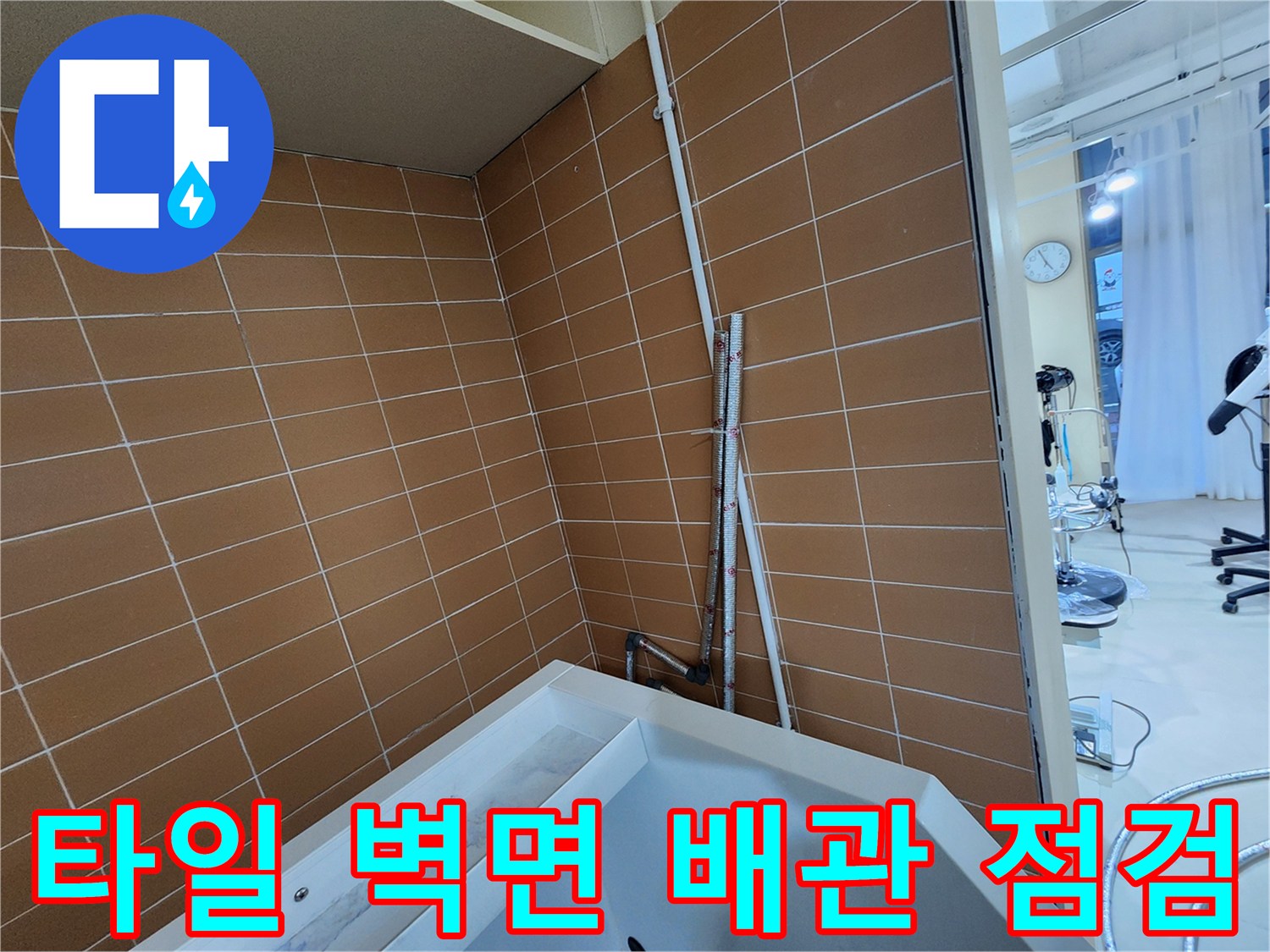갈색 타일 벽면에 설치된 수직 배관과 연결 부위