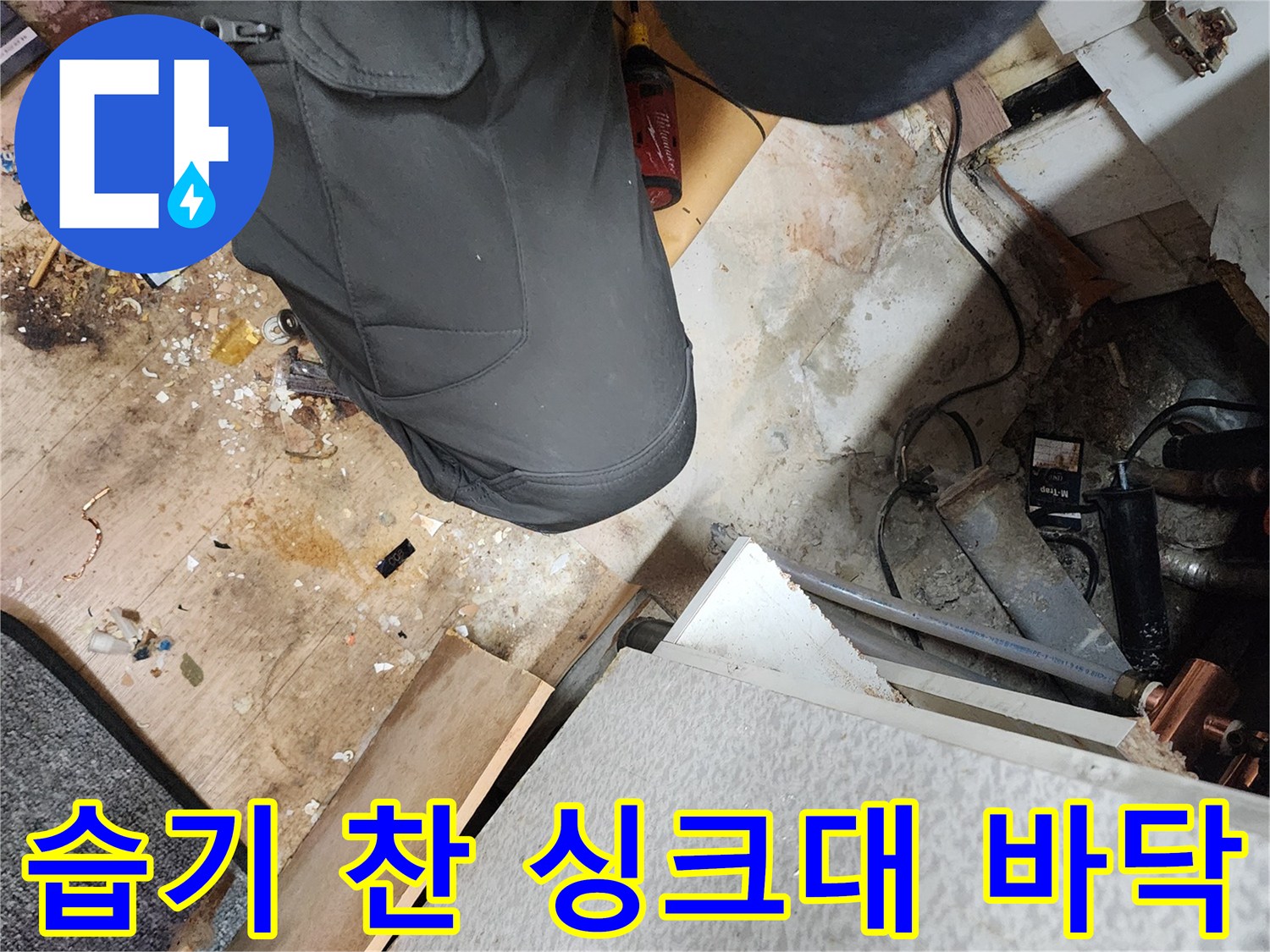 싱크대 하부 배관 주변의 젖은 콘크리트와 파헤쳐진 바닥