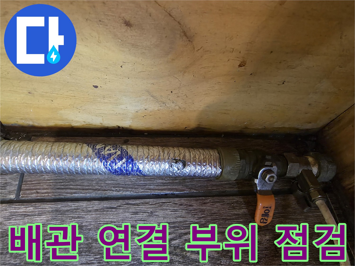 은색 보온재 배관과 주황색 밸브 핸들 근접 촬영