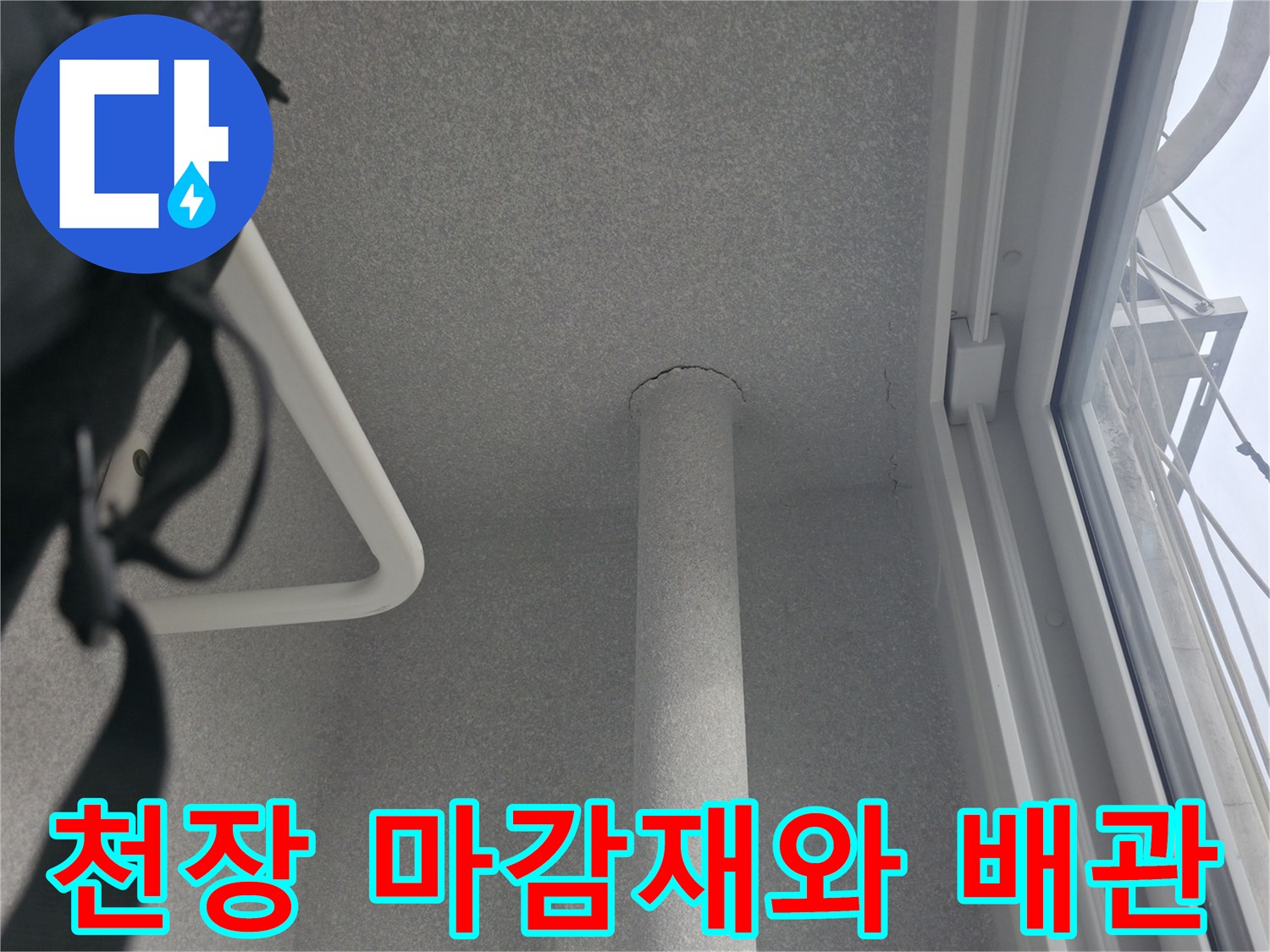 천장 마감재 사이로 노출된 수직 배관의 모습입니다.