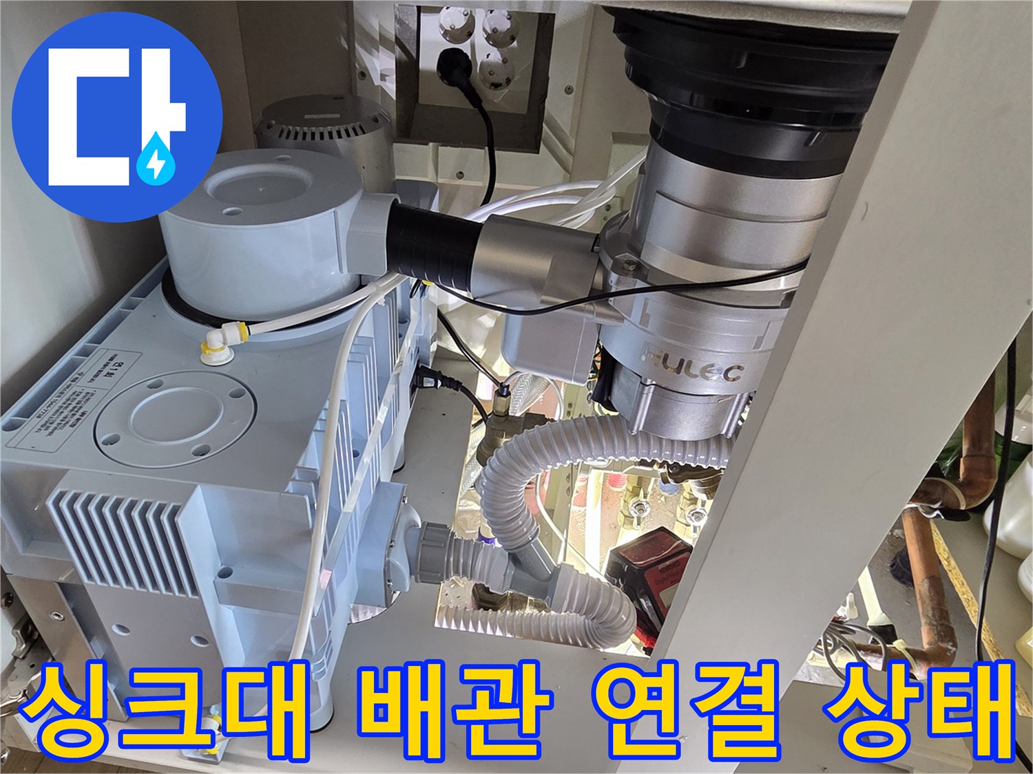 하얀색 배관과 압력계가 설치된 싱크대 하단 내부 전경