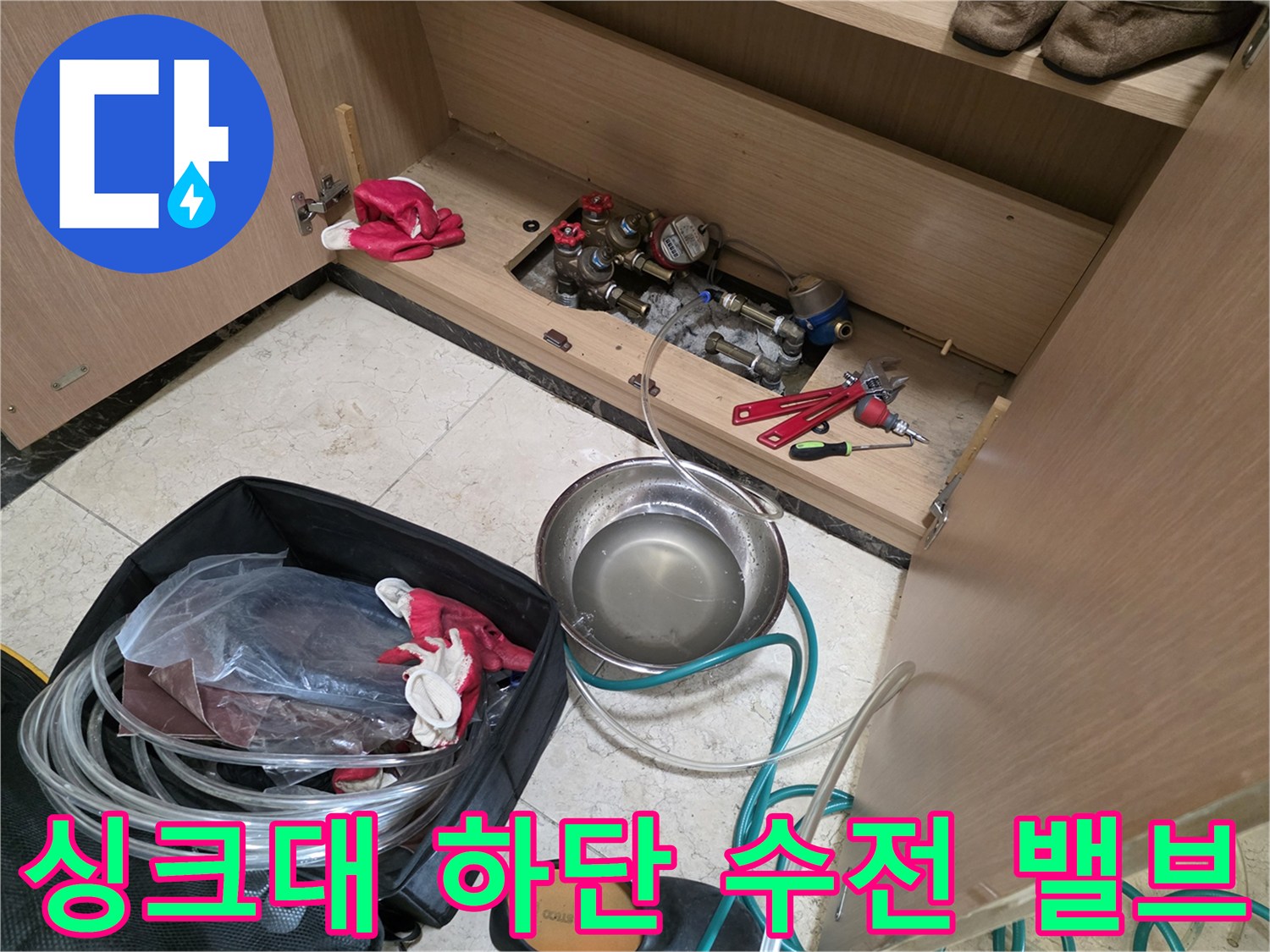 싱크대 아래쪽 배관과 교체용 공구가 놓인 현장 사진