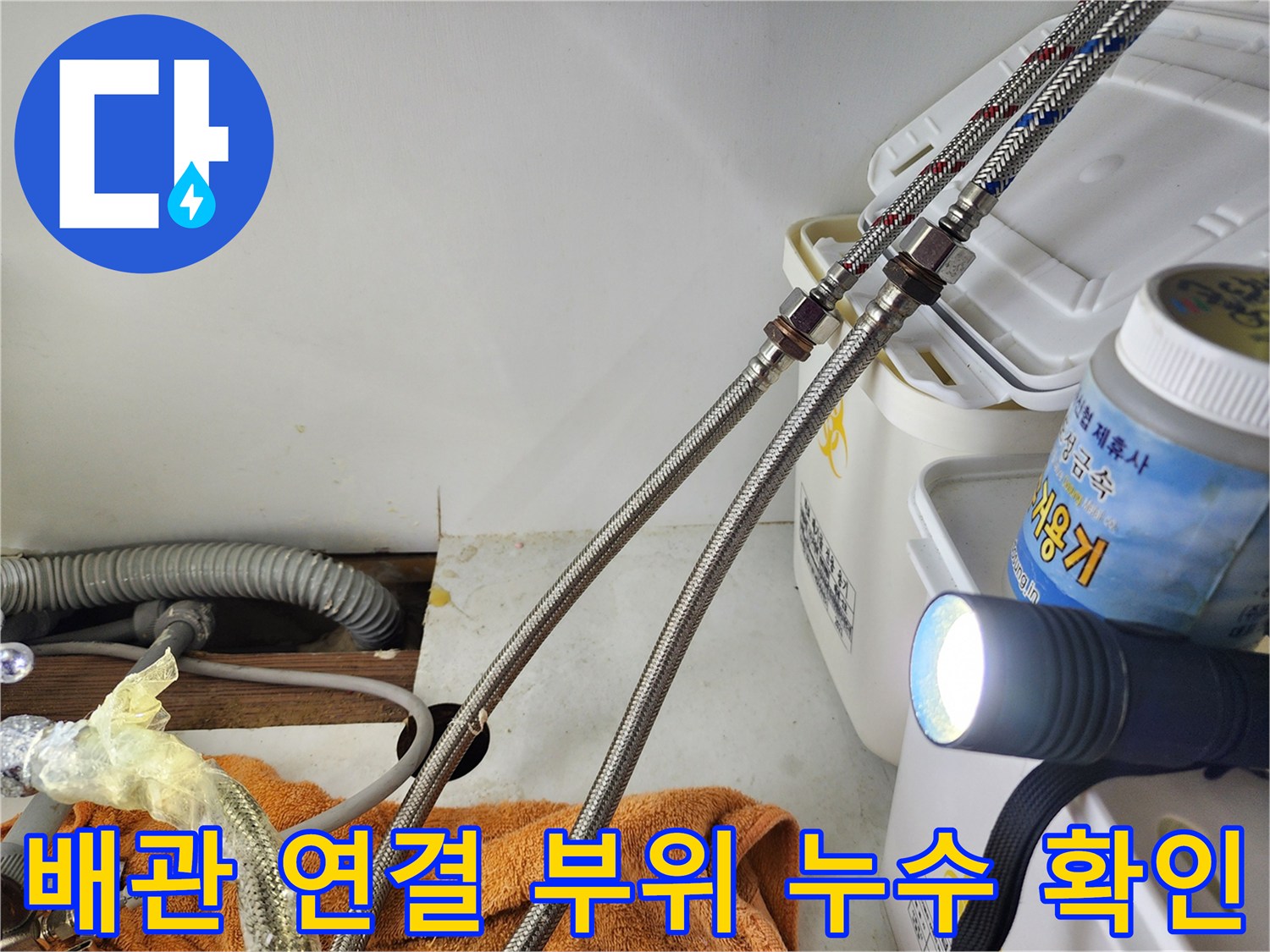 손전등 빛으로 비춘 싱크대 하부 밸브와 호스 상태