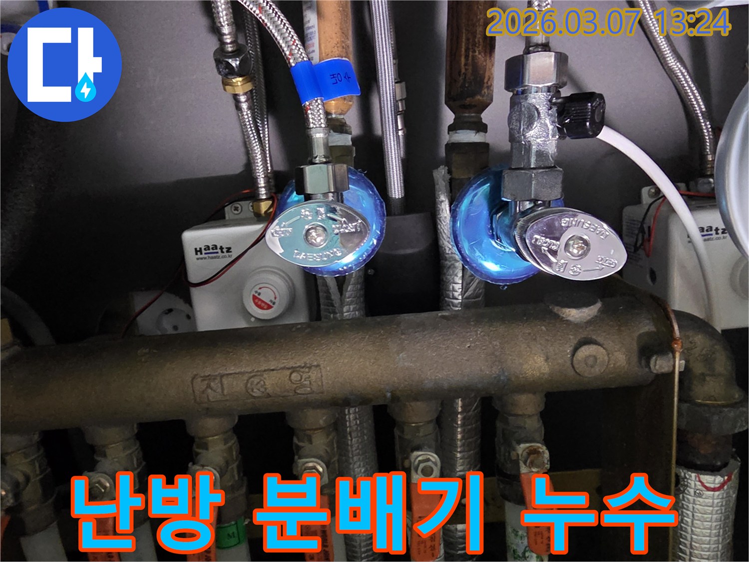 엔지니어가-난방 분배기 주변에서-발생한 누수 흔적을-세심하게 확인하는 장면입니다.