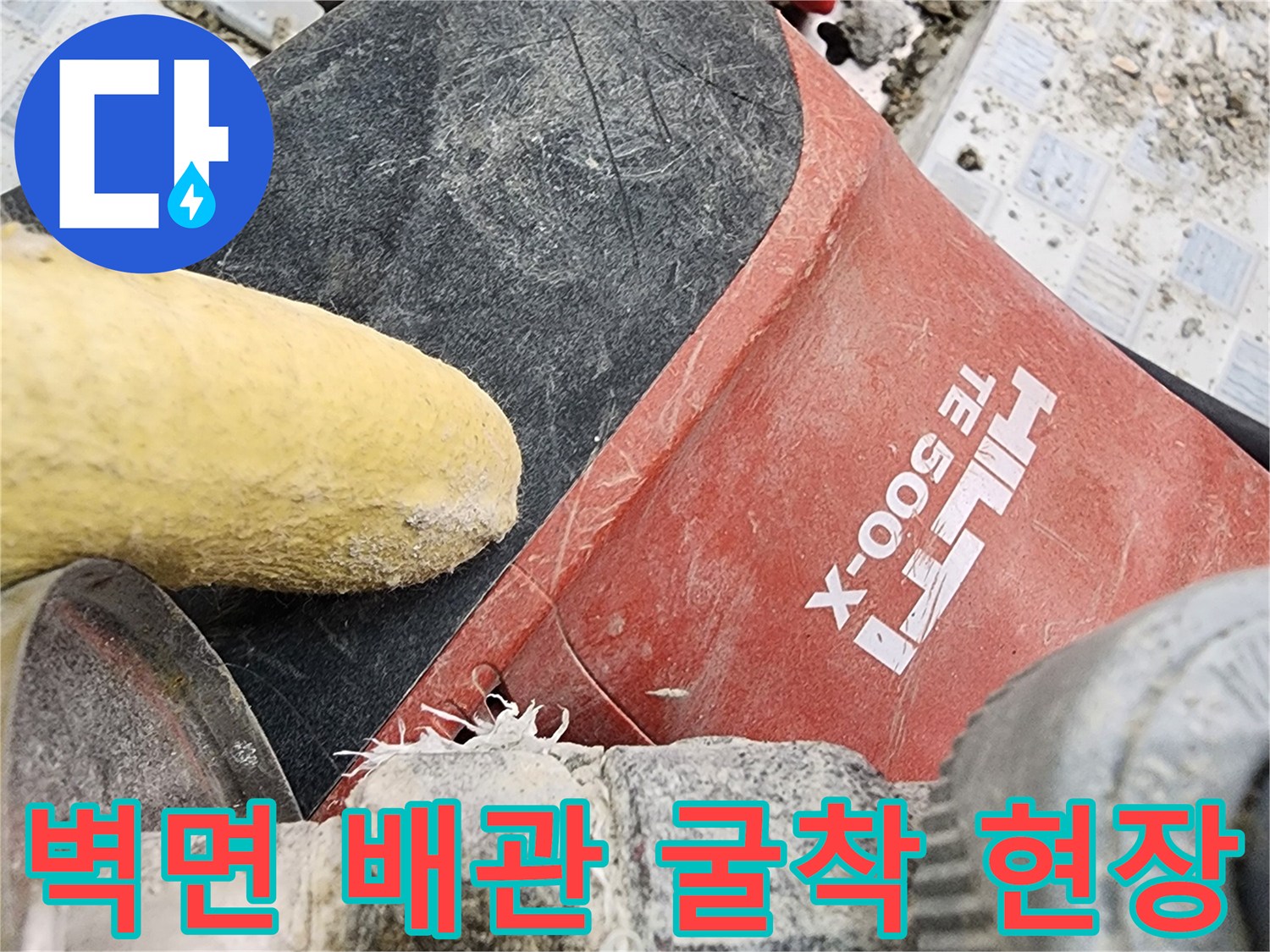 파손된 타일 조각들과 작업용 드릴이 놓여 있는 누수 공사 부위