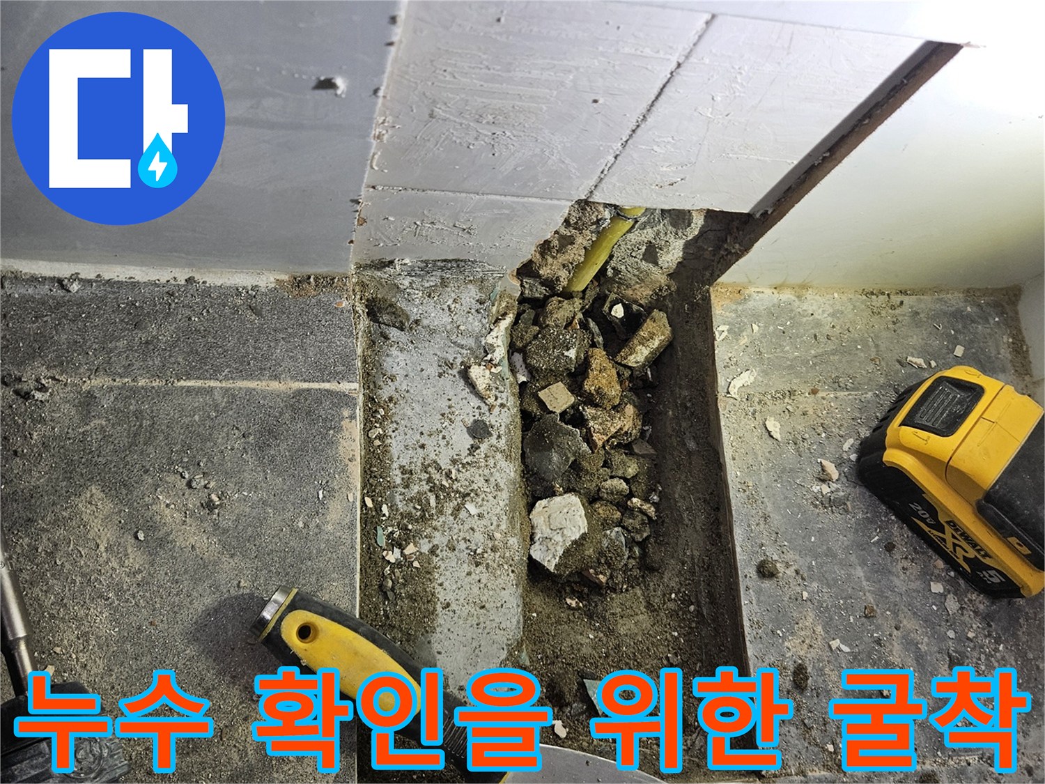 제거된 타일 조각과 파헤쳐진 바닥 사이의 배관 노출