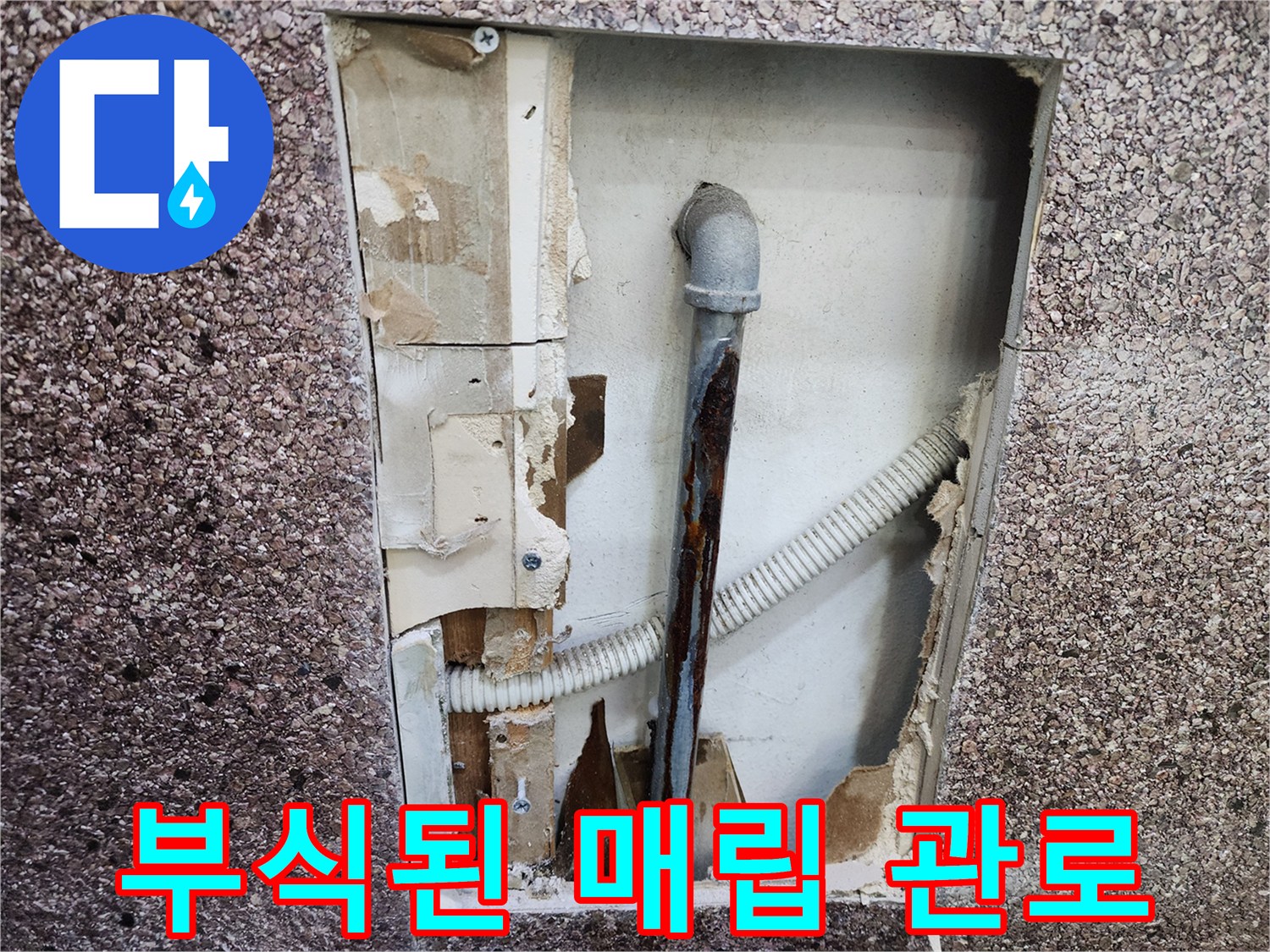 벽면 타공 부위-녹슨 금속 파이프와 배수 호스