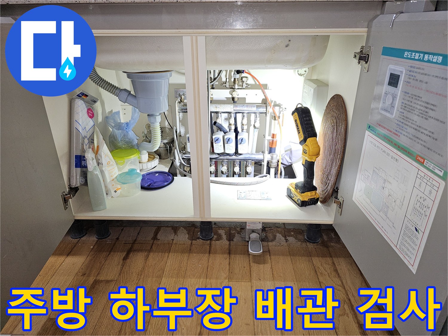 싱크대 밑 분배기 주변의 배관들과 작업 장비가 있는 모습