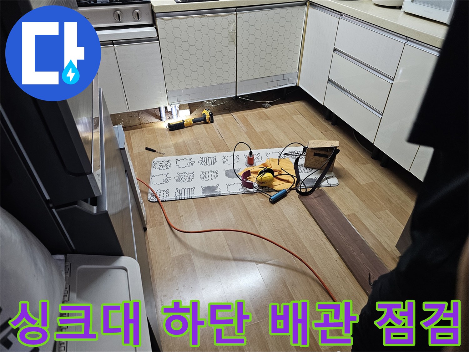 싱크대 아래쪽 공간 - 누수 지점을 찾기 위해 장비를 사용 중인 현장