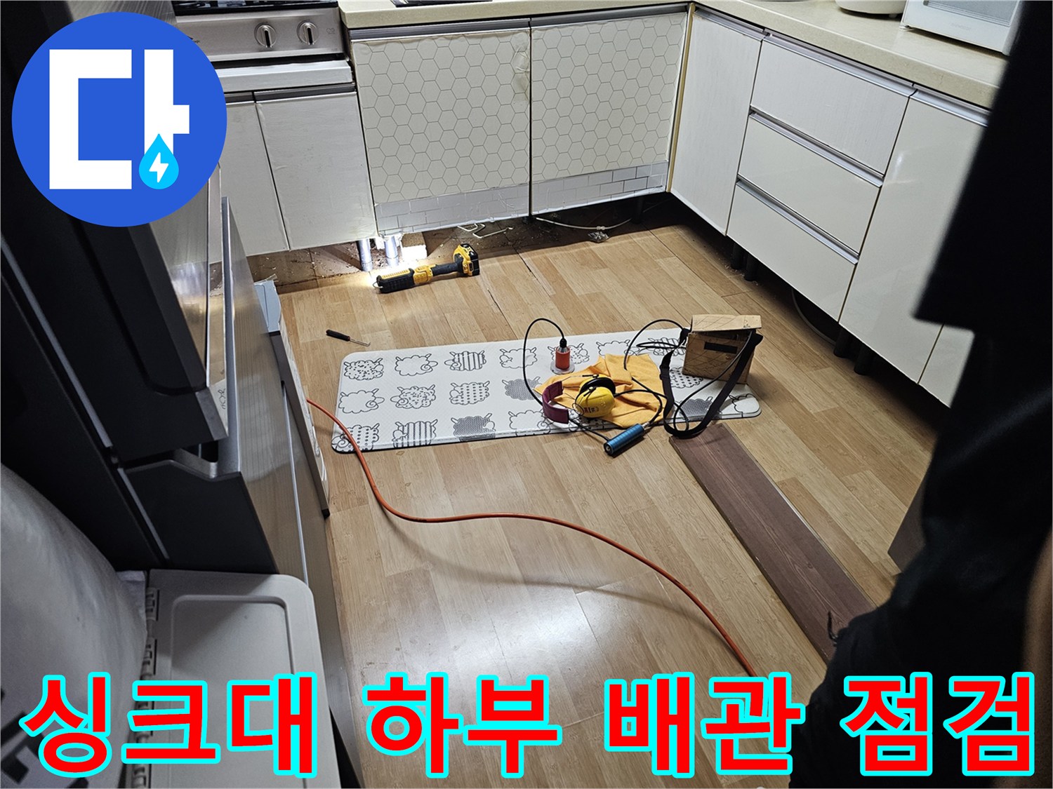 싱크대 하단 가구 아래 배관 상태를 확인하는 모습
