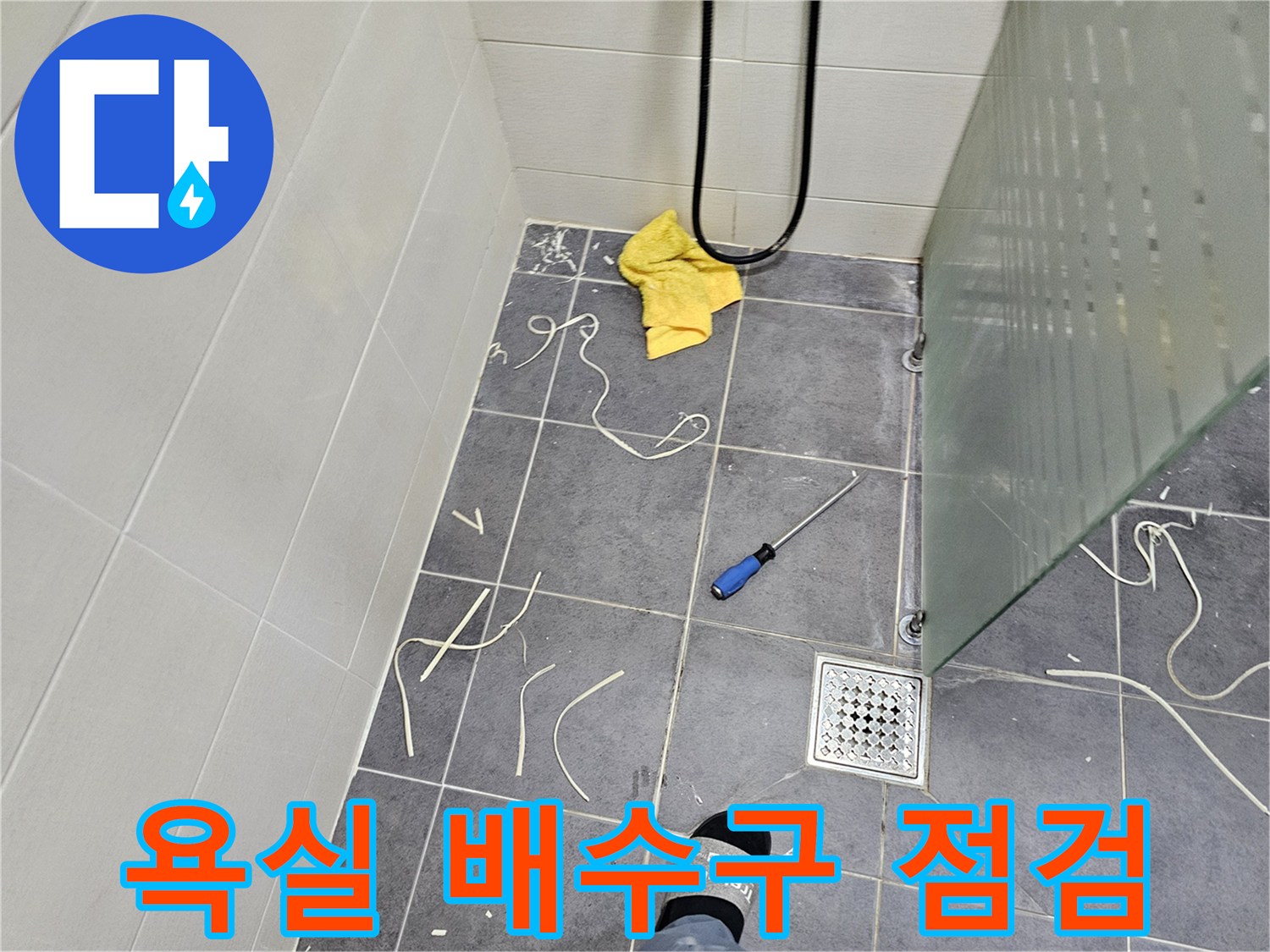 화장실 바닥의-배수구 주변과 떨어진 자재 조각들