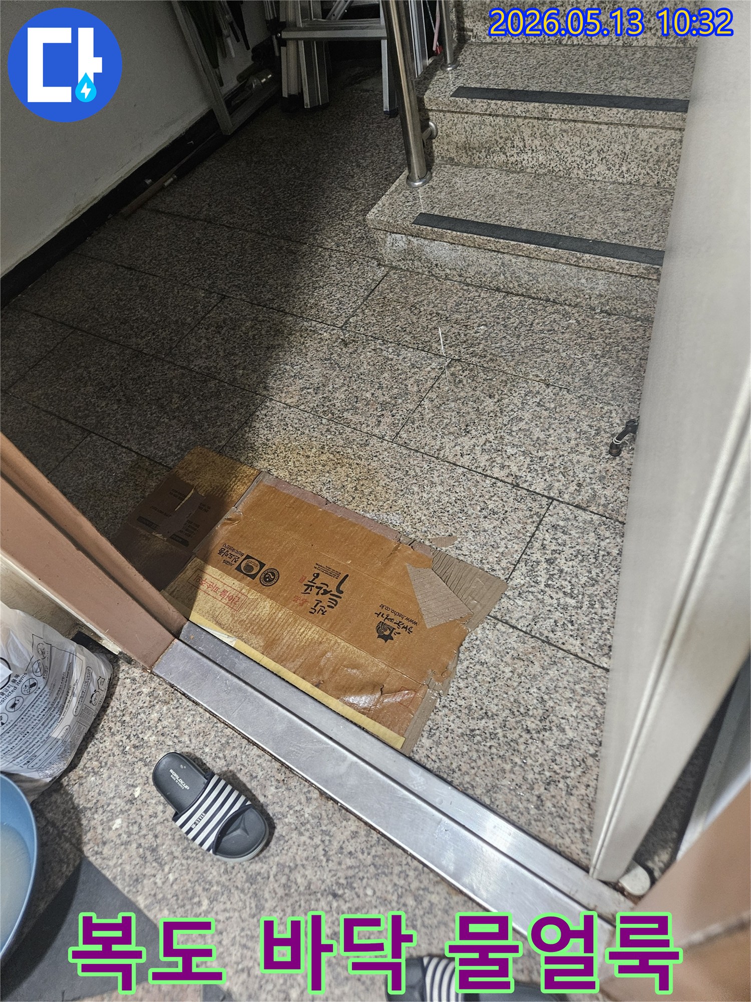 복도 바닥에 물얼룩과 젖은 박스가 놓여있어-누수로 인한 바닥 손상이 우려됩니다