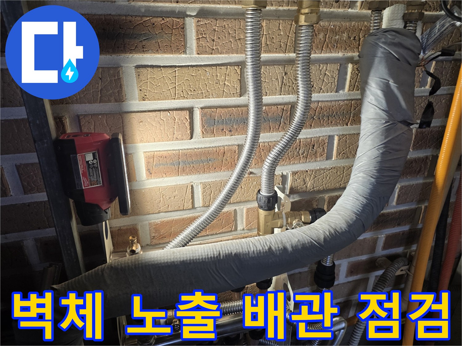 벽돌 벽면에 연결된 은색 주름관과 검은색 보온재 부위
