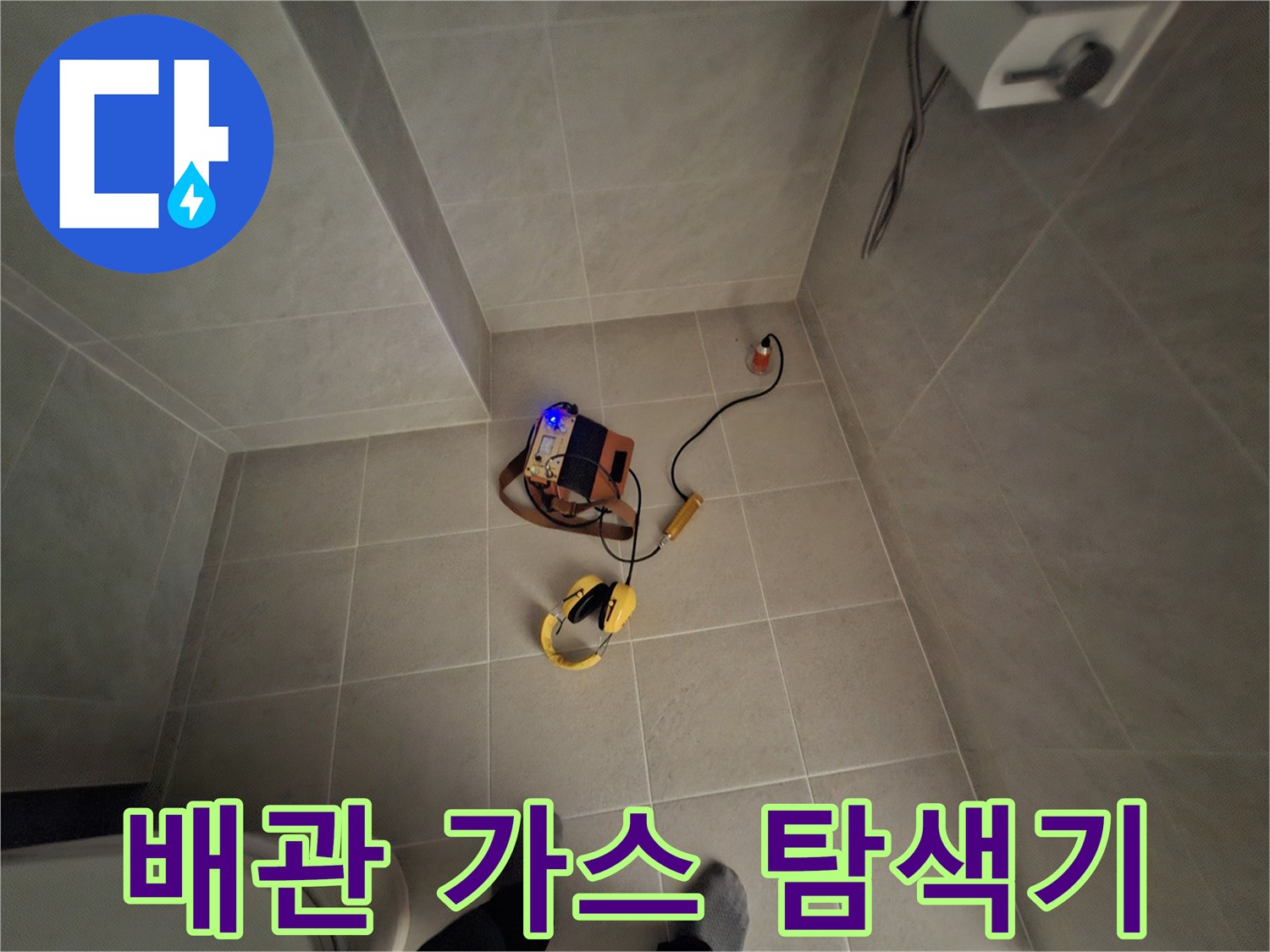 타일 바닥에 놓인 노란색 누수 탐지 장치와 선