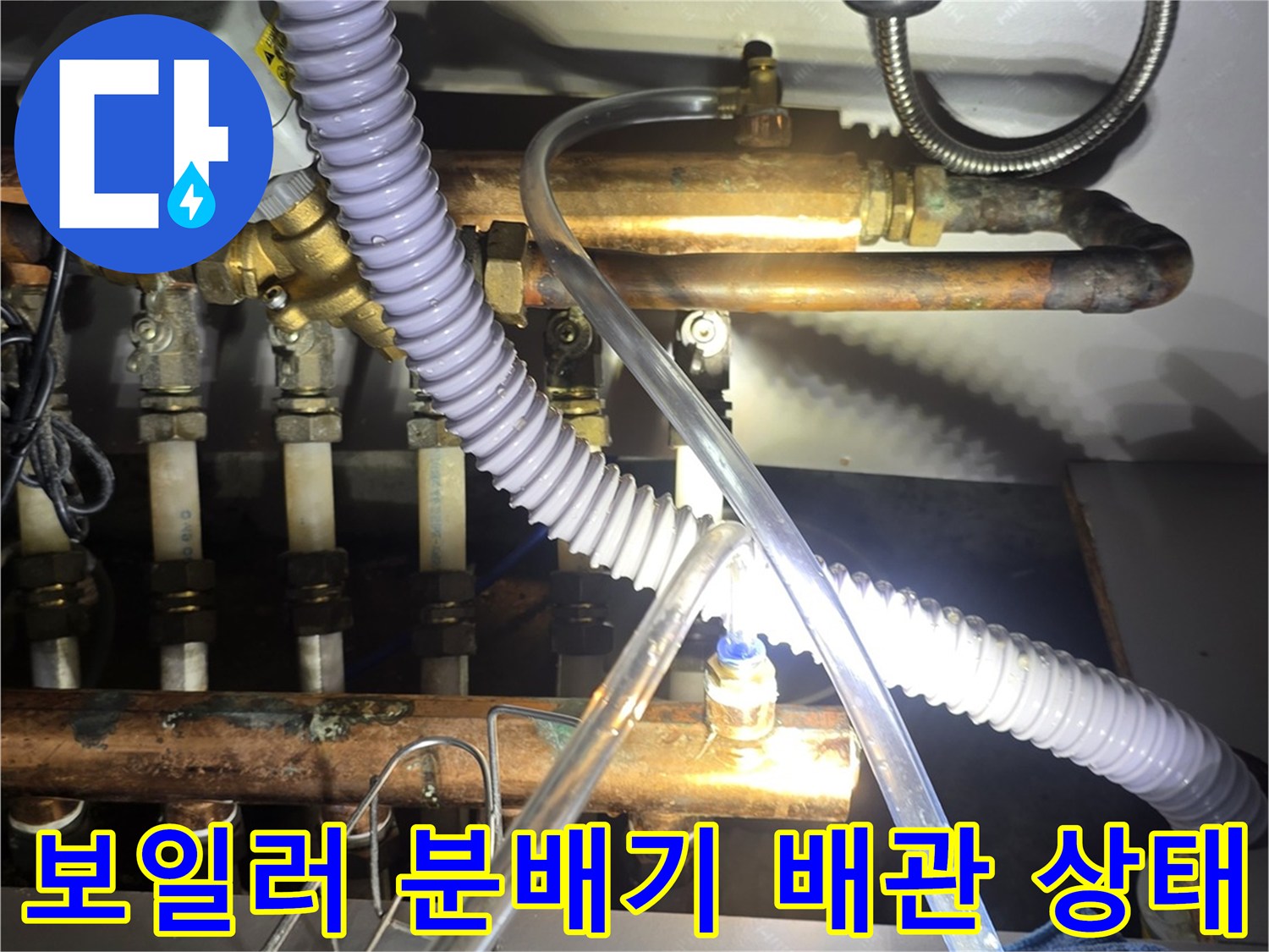 금속 배관과 흰색 호스가 연결된 싱크대 밑 분배기 구조