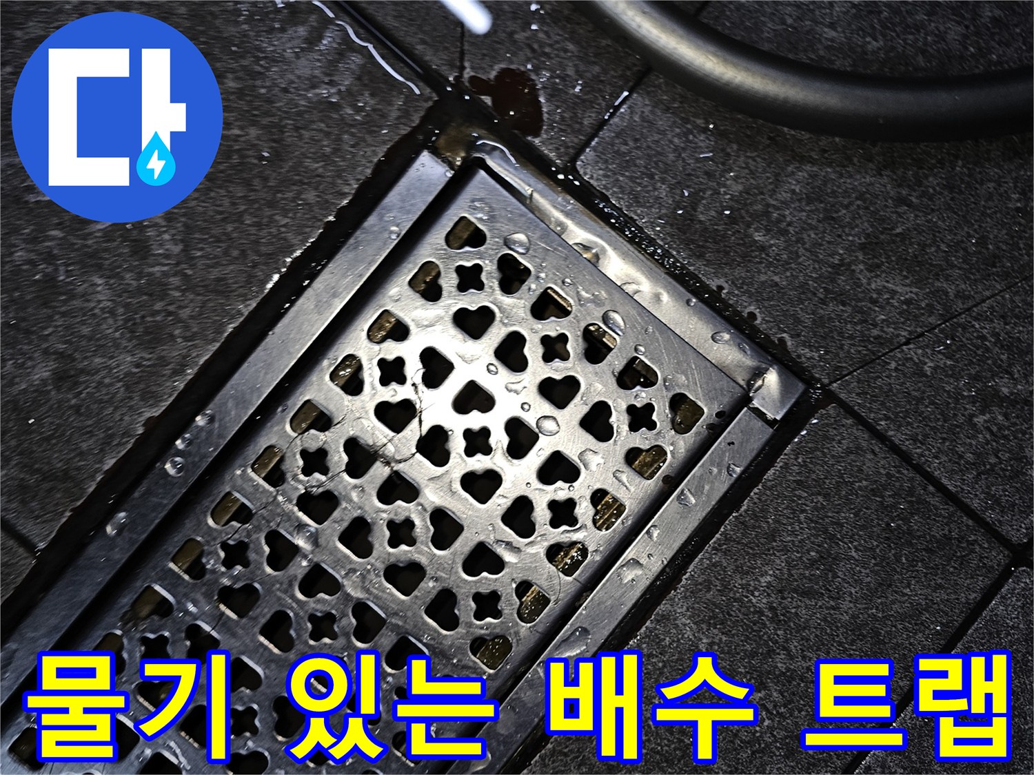젖은 타일 위에 놓인 금속 배수구 덮개