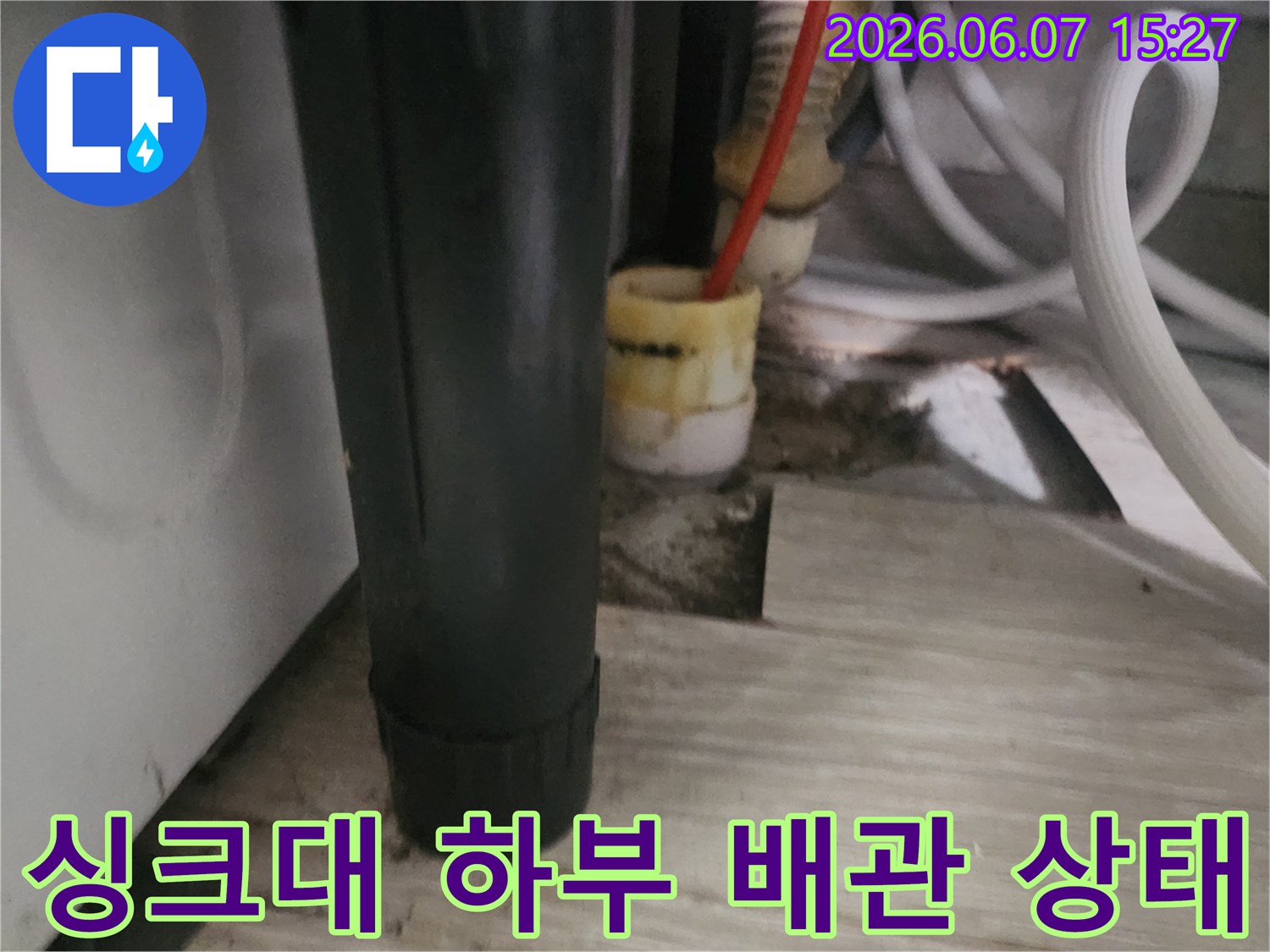 싱크대 아래쪽-복잡하게 연결된 배관과 호스의 근접 사진입니다.