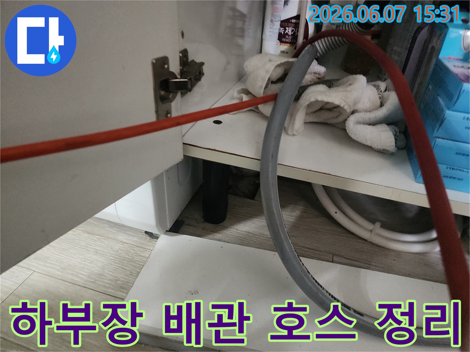 싱크대 하부 배관 주변의 작업용 붉은색 호스 모습