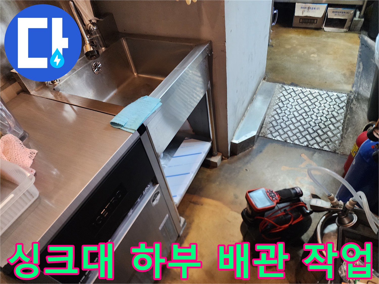 싱크대 하부장 아래 설치된 배관 청소 장비와 주변 환경