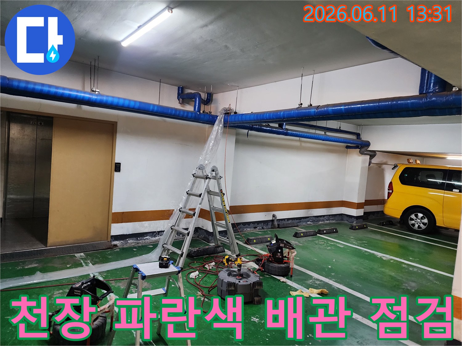 지하주차장 천장에 설치된-파란색 대형 공용 배관과 작업 도구
