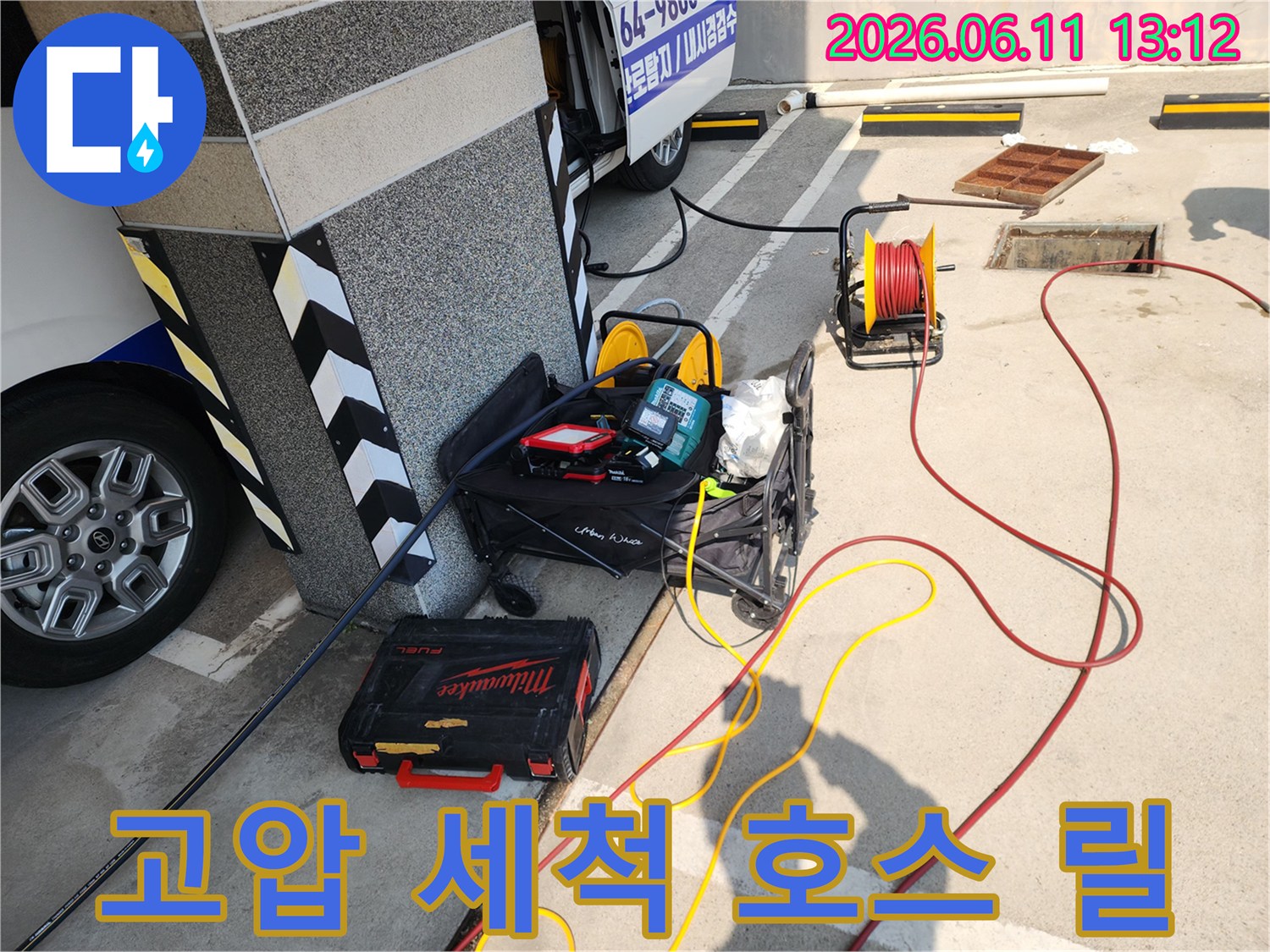 건물 기둥 옆에 준비된 배관 청소용 고압 호스와 공구함