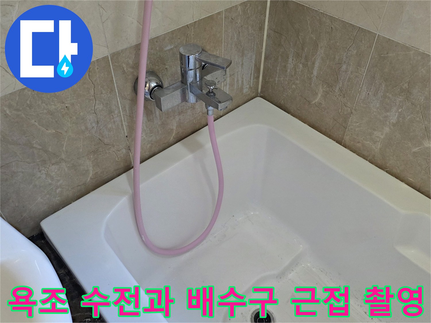 욕조 내부의 샤워 수전과 분홍색 호스가 연결된 모습입니다.