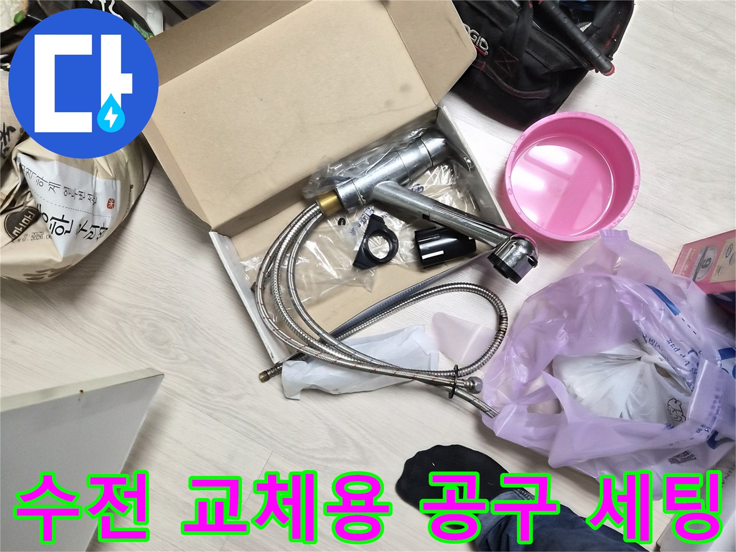 바닥에 펼쳐진 새 수전 제품과 작업 장비 구성
