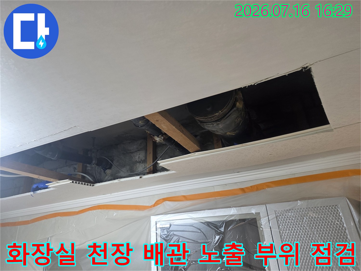 천장 안쪽의 하수도 및 오수 배관 연결부 상태를 면밀히 조사하는 장면