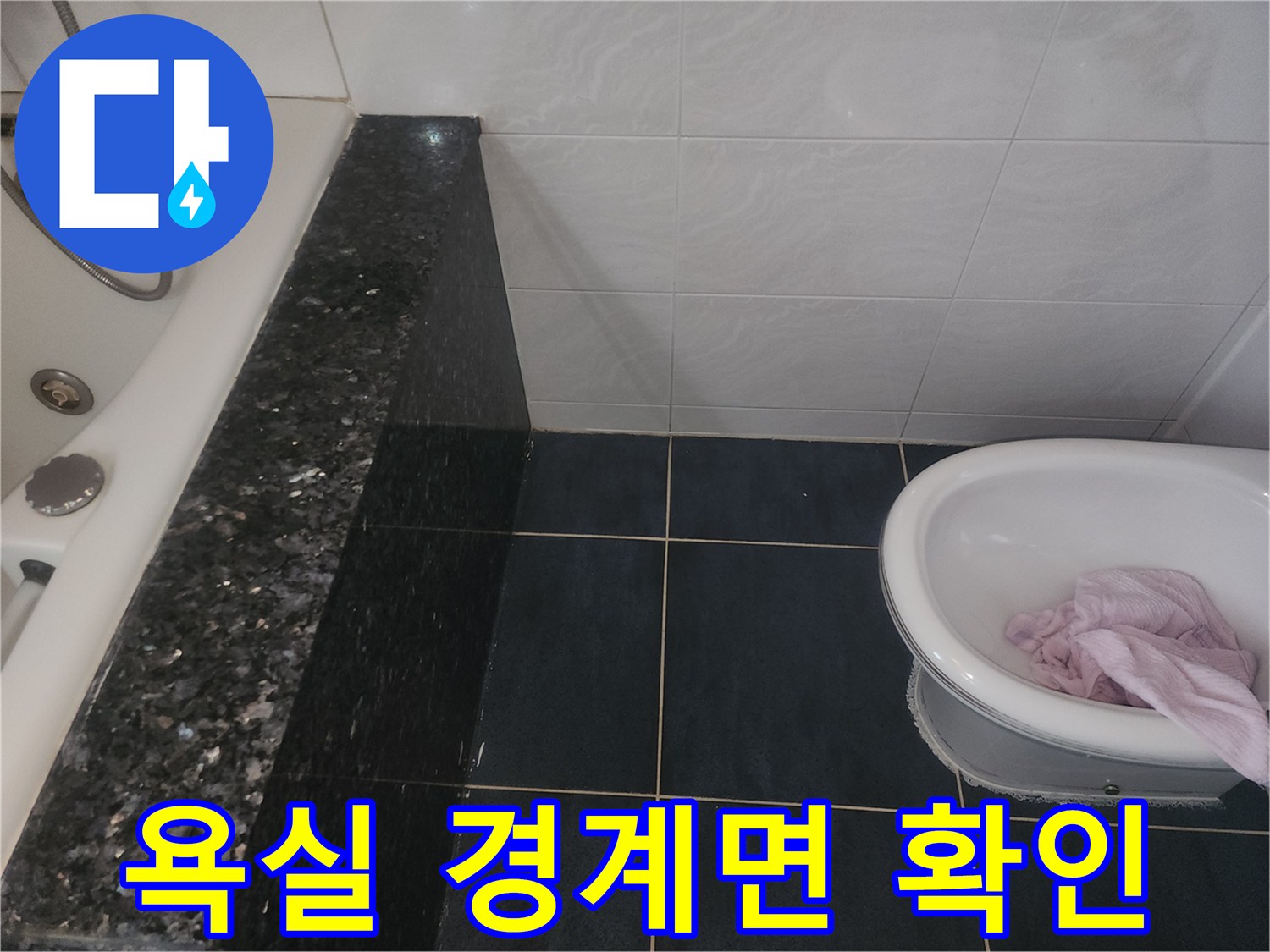 어두운 색상의 타일과 흰색 욕조가 연결된 부분