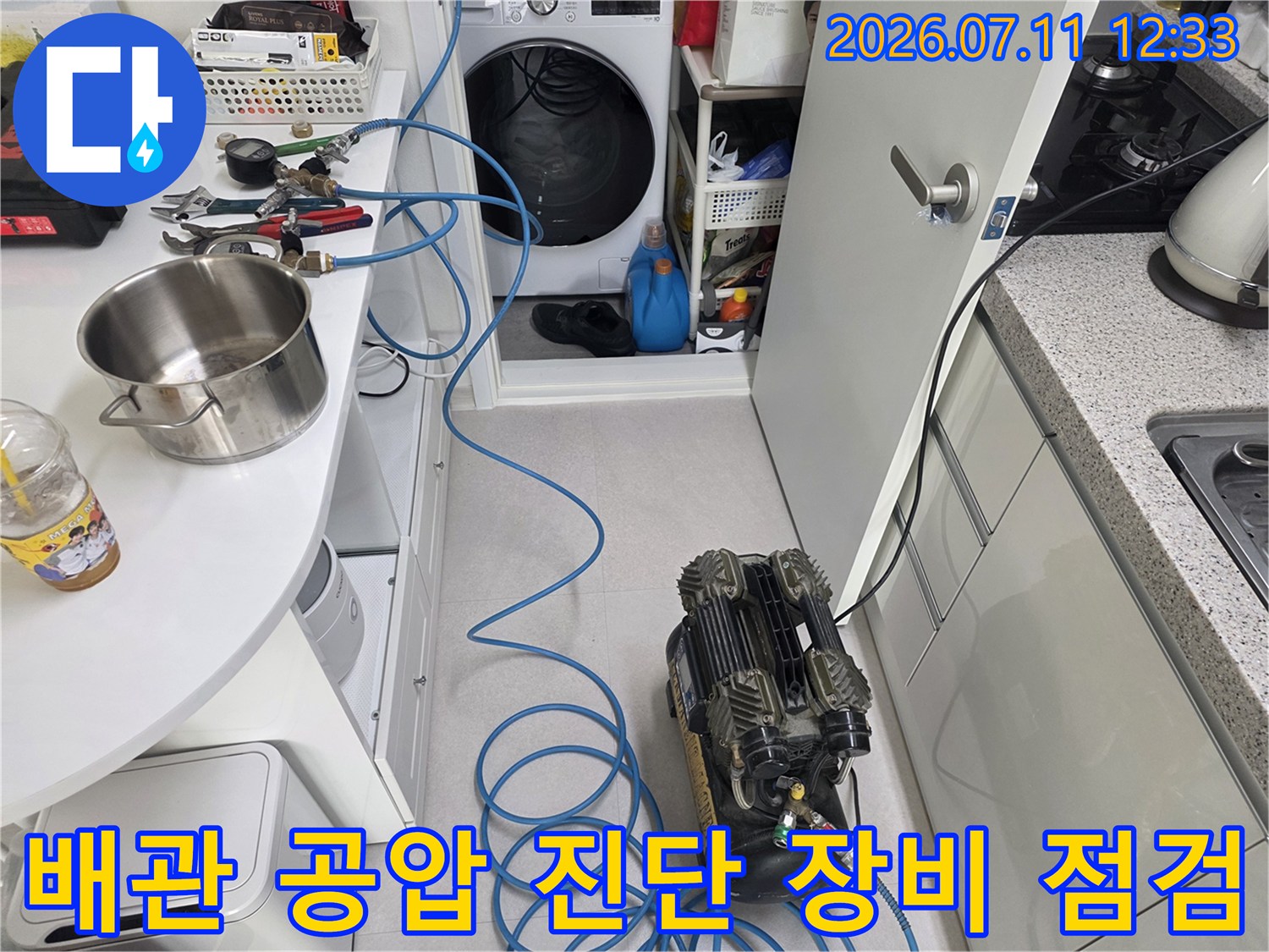 배관에 연결된 파란색 호스와 전문 누수 탐지용 압력 측정기