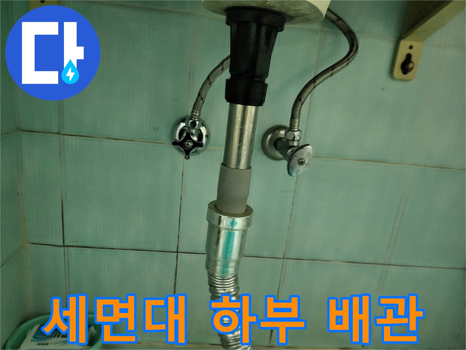 세면대 아래쪽-금속 재질의 급수 호스와 배수관 연결 부위 모습