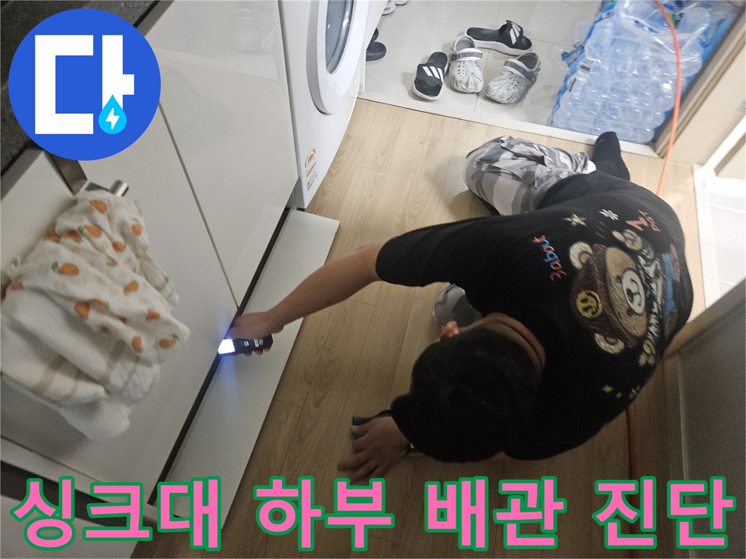 싱크대-하단-배관-연결부를-손전등으로-조사하는-모습