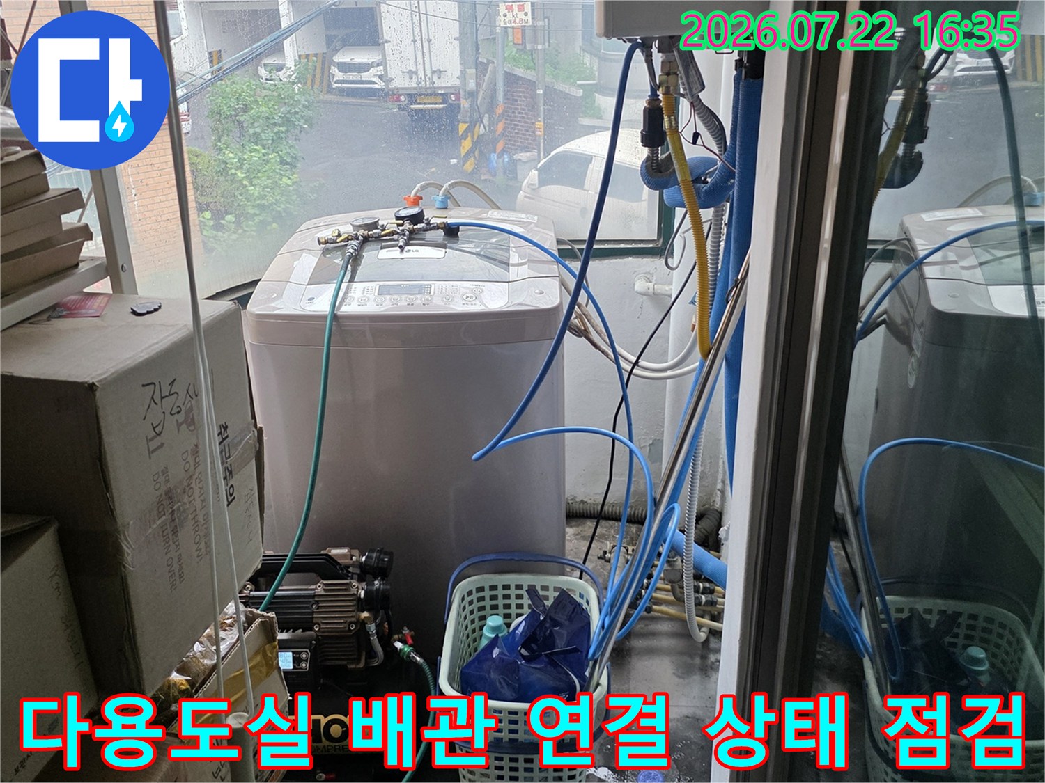 다용도실 내부에 설치된 하얀색 가전제품과 파란색 수도 배관-연결 부위 모습