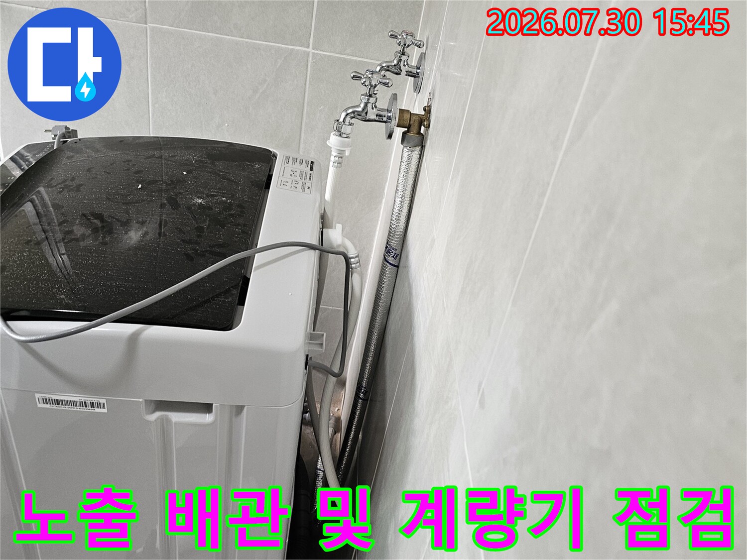 세탁실 공간에 설치된 수도계량기와 노출형 금속 배관의 모습