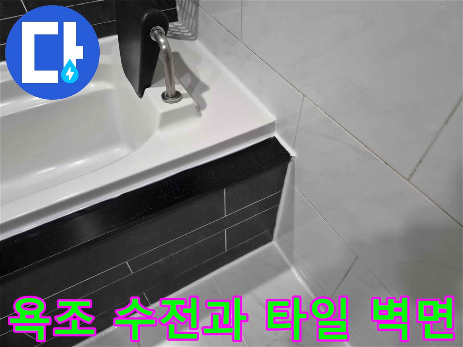 욕조 수전 부근의 흰색 욕조와 검은색 타일 경계선