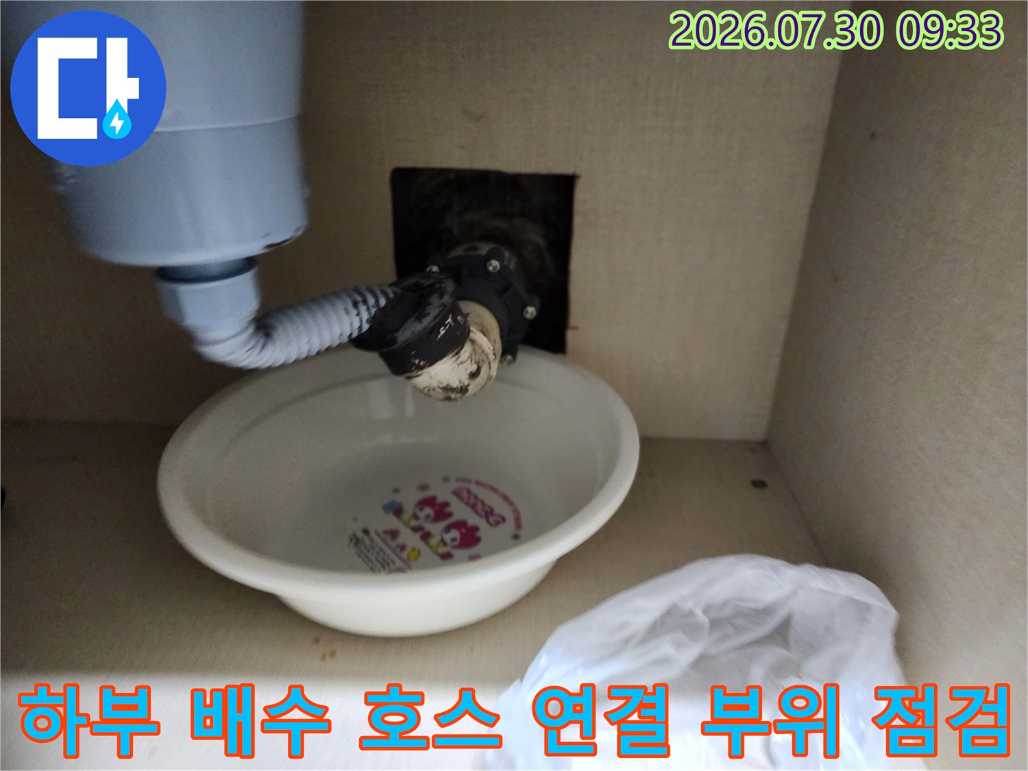 싱크대 밑바닥에 위치한 하수 배출구와 연결된 호스의 노후 상태를 살피는 장면