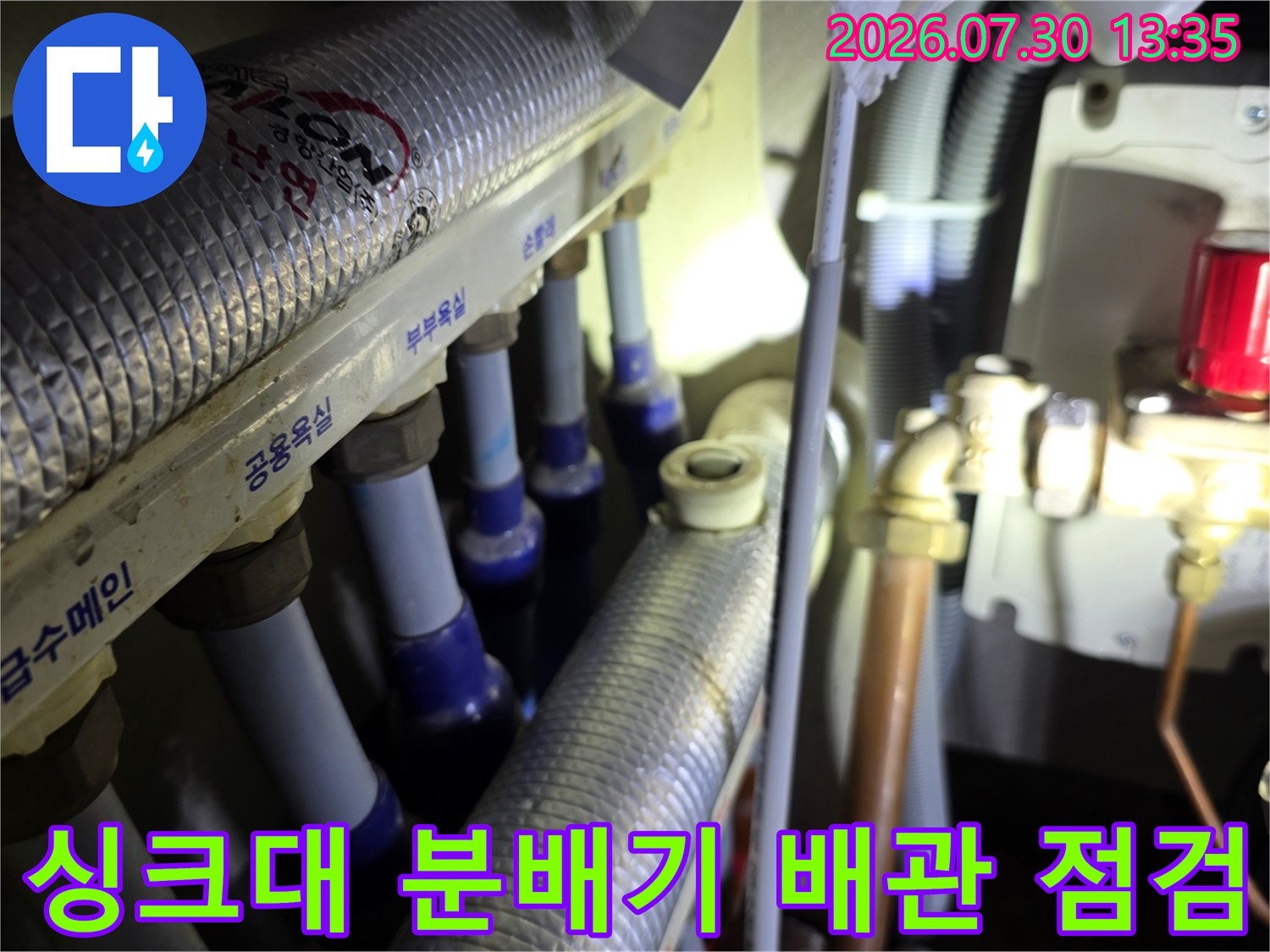 싱크대 하단부 온수 및 냉수 분배기 배관 수선 작업 장면