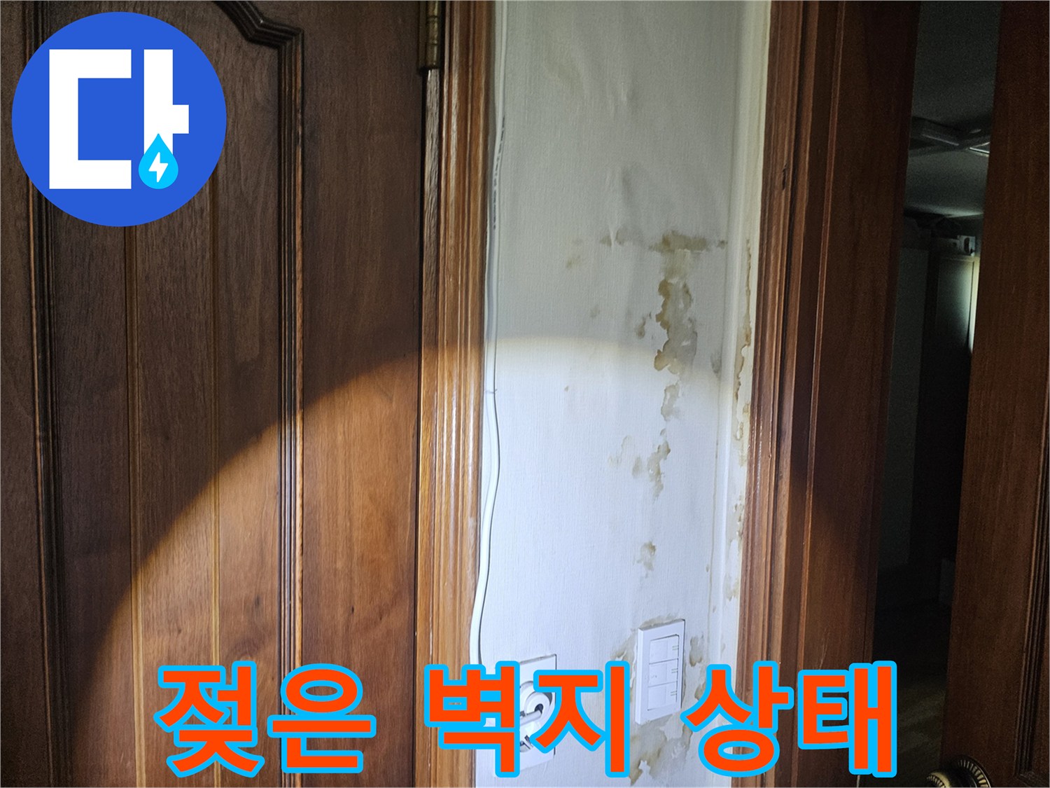 현관 입구 콘센트 주변의 젖은 벽지 모습