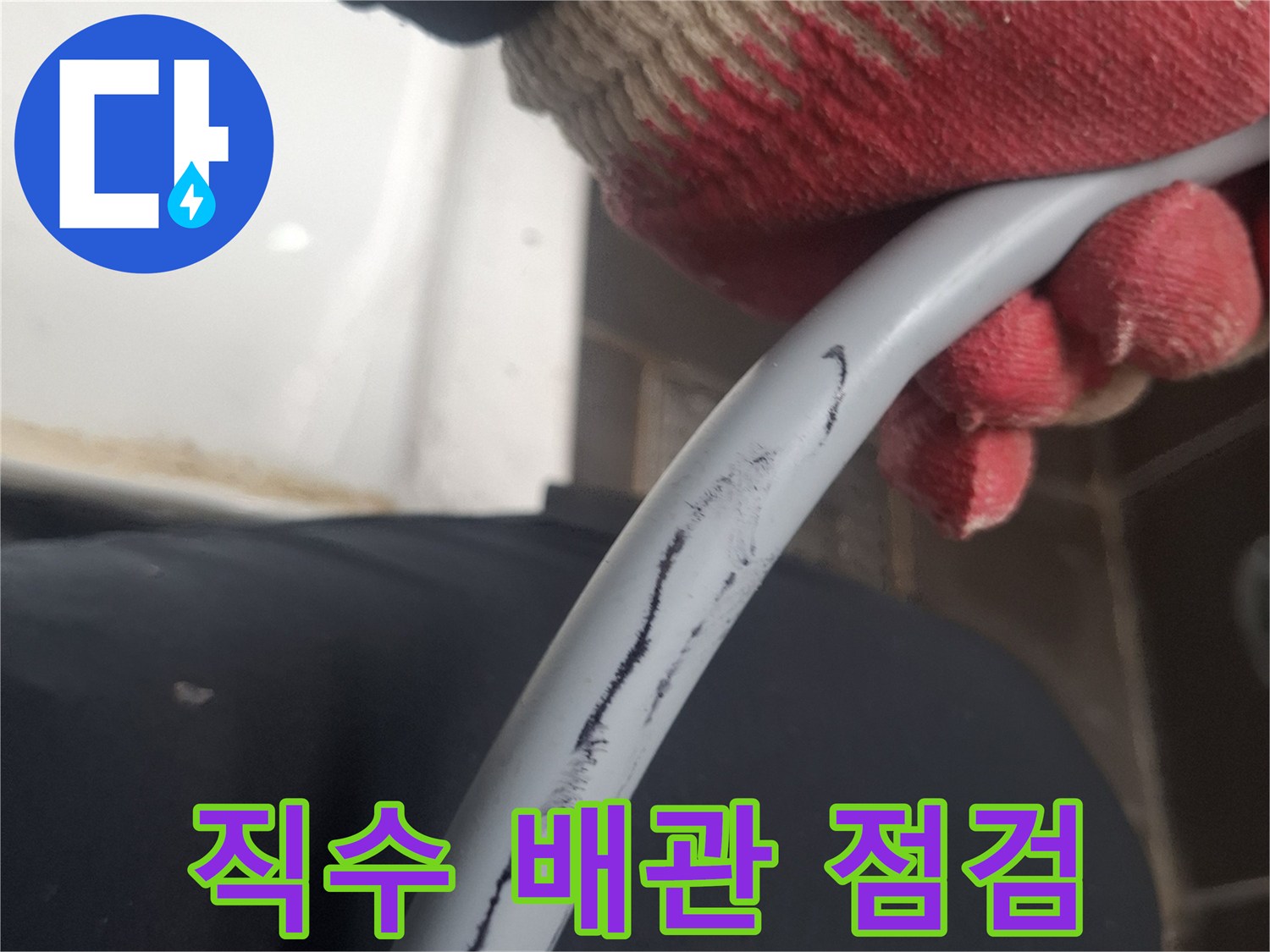 장갑을 낀 손으로 회색 배관을 잡고 있는 모습