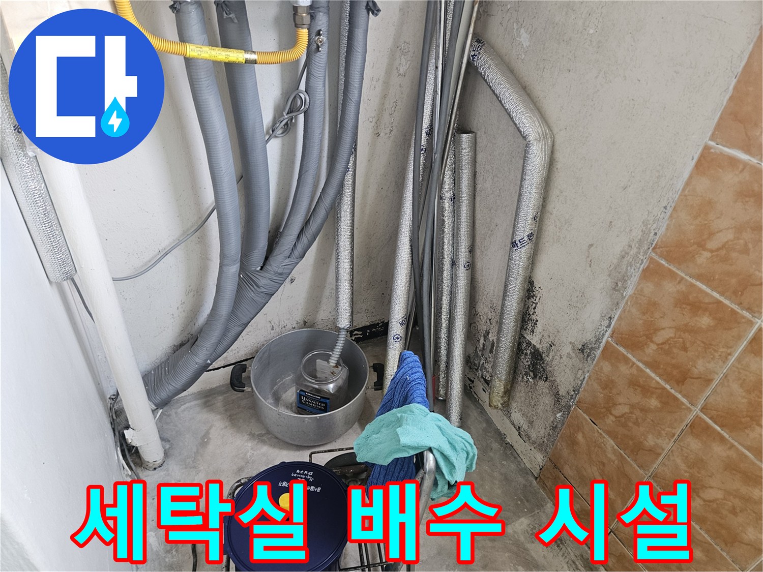 세탁실-벽면의-배관들과-연결된-배수-호스의-현장-사진