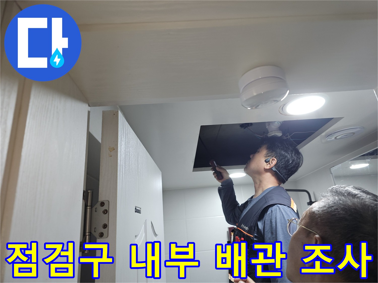 점검구를 열고 천장 배관을 살펴보는 작업자 모습