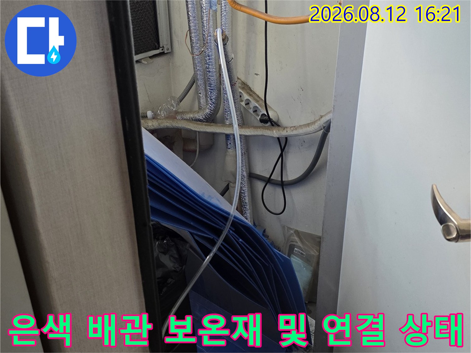 흰색 기계 장치 주변으로 은색 단열재가 씌워진 여러 가닥의 배관들이 배치된 사진